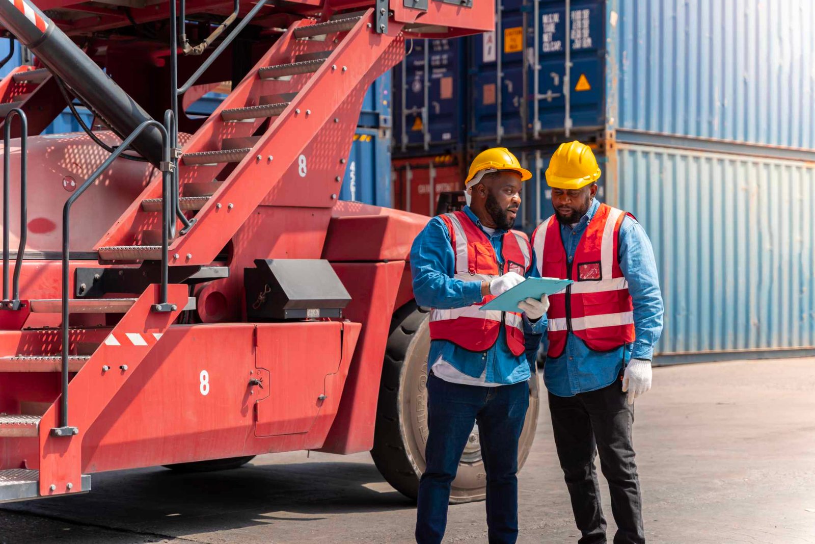 Two workers reviewing shipment paperwork at a container yard